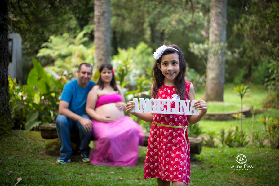 A FILHA DO CASAL SEGURA O LETREIRO COM O NOME DA IRMÃ PARA AS FOTOS DO BOOK DE GESTANTE