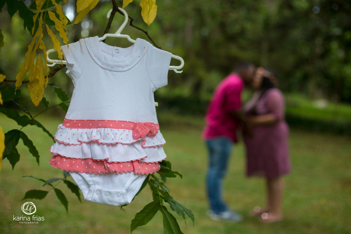 OS PAIS ESTÃO SE BEIJANDO AO FUNDO ENQUANTO A FOTOGRAFA DE FAMILIA, KARINA FRIAS, REGISTRA O MOMENTO.