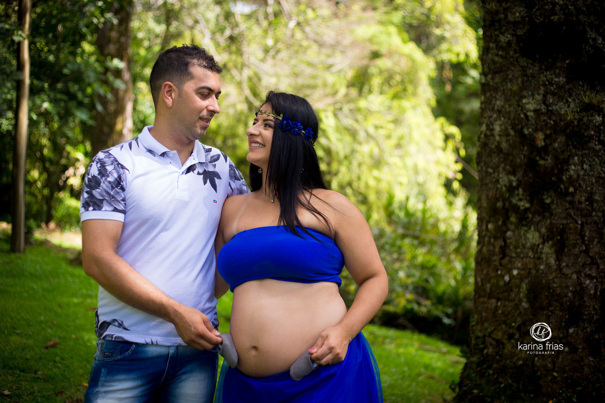 O CASAL SE OLHA E SEGURA O SAPATINHO DO BEBE ENQUANTO A FOTOGRAFA DE GESTANTE, KARINA FRIAS CLICA OS DOIS