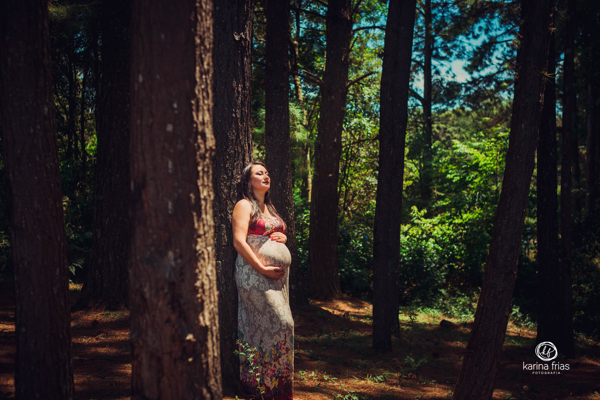 no ensaio de gestante, a modelo encosta na arvore e respira fundo