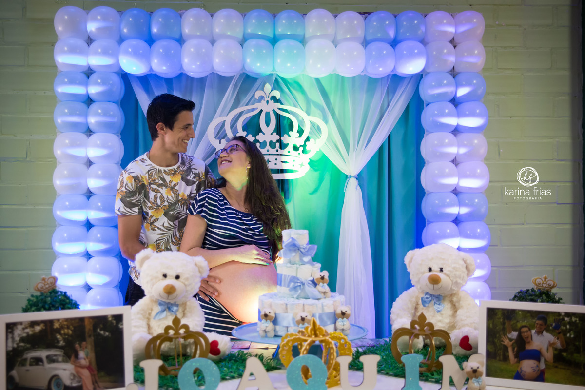 OS PAIS SE OLHAM ENQUANTO A FOTOGRAFA DE FAMILIA, KARINA FRIAS, FAZ A FOTO DO CHA DE FRALDAS