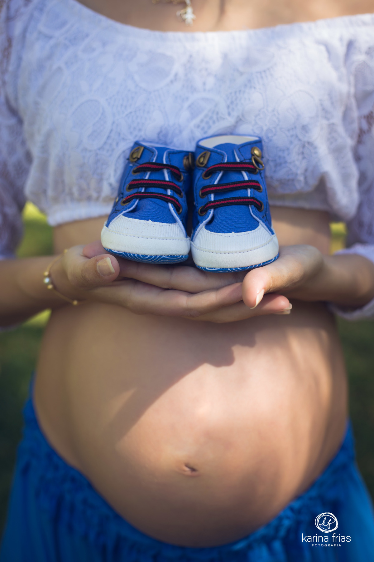 a gestante segura o sapatinho para as fotos do book externo