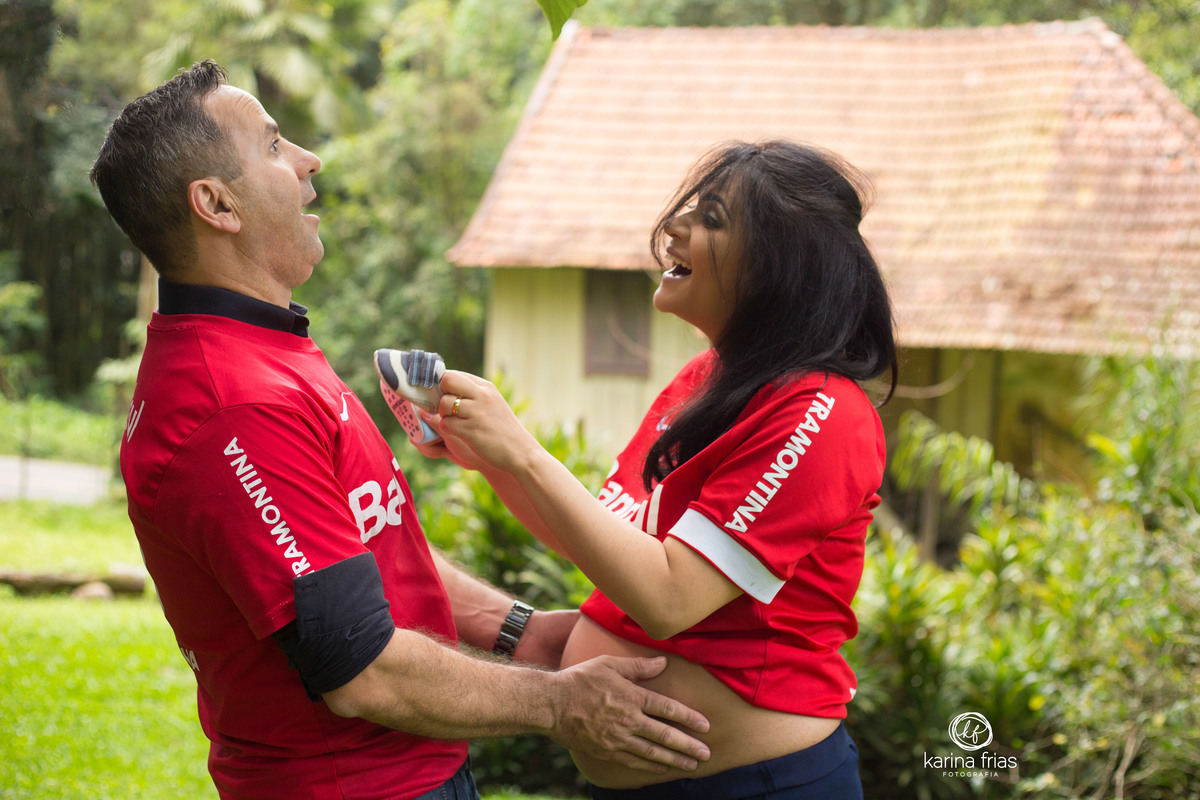 os pais brincam com o sapatinho do bebe, utilizado como acessorio no ensaio de gestante