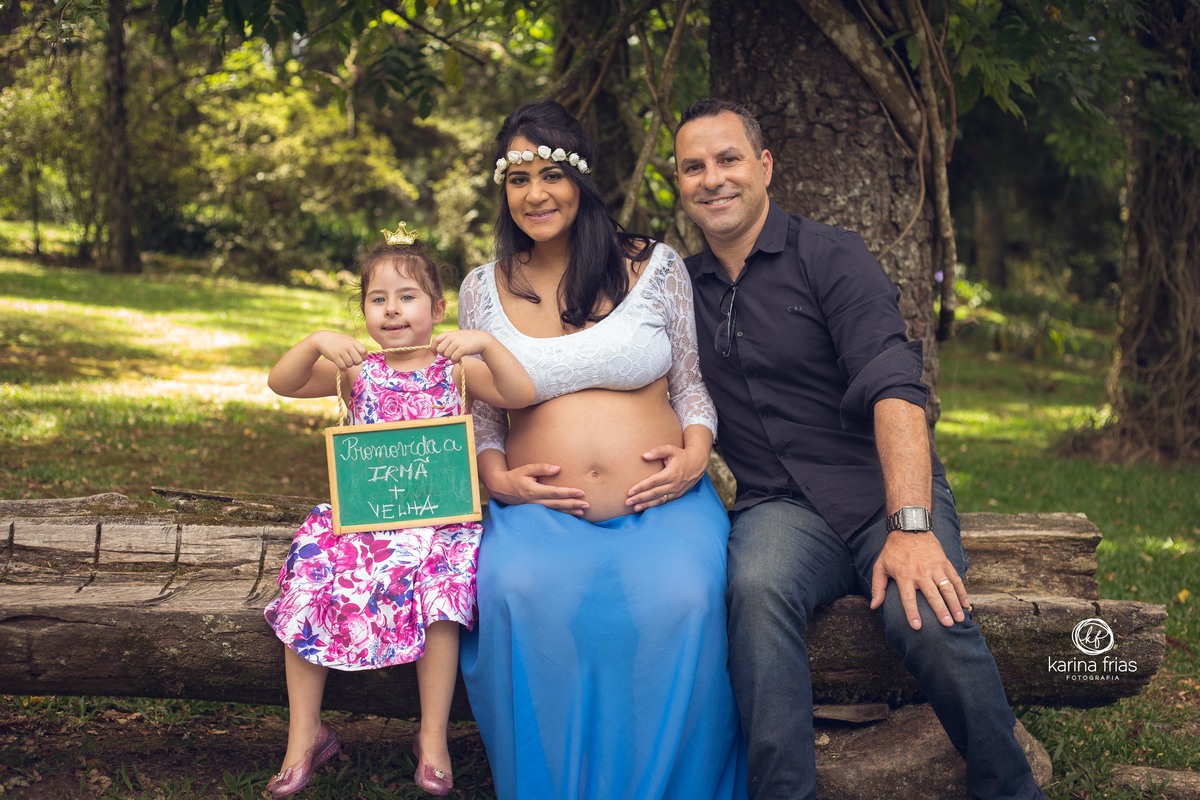 a irma segura plaquinha de irma mais velha no ensaio externo de gestante