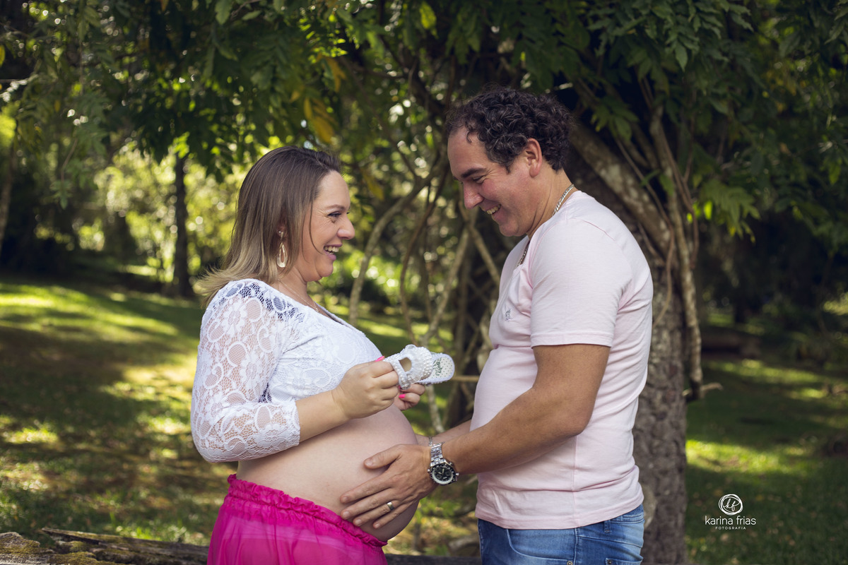 o pai olha a barriga da gestante durante a sessão de fotos