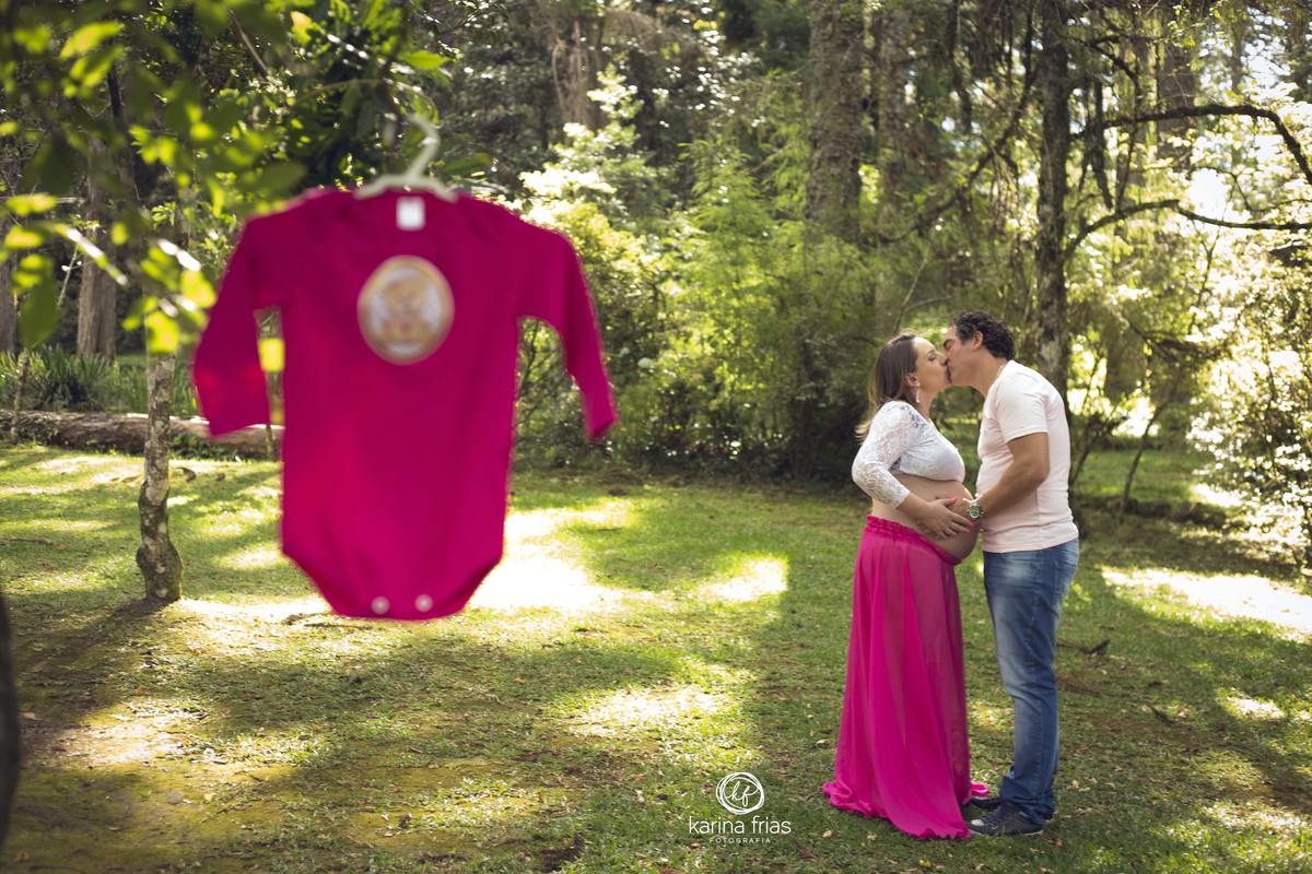 a roupinha esta pendurada e os pais estao ao fundo no ensaio externo