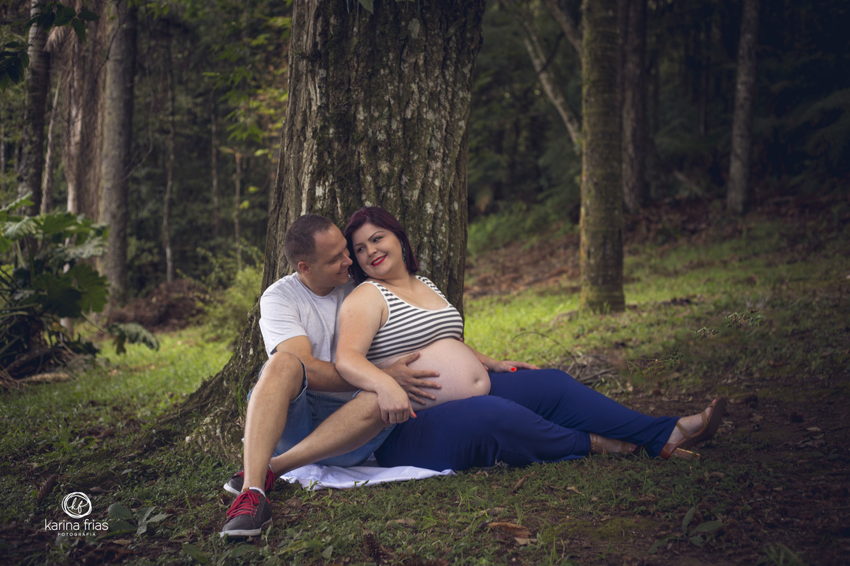 os pais estao sentados se olhando na hora do ensaio de gestante