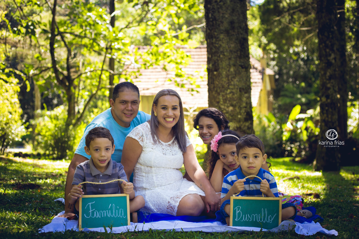 a famila esta sentada segurando a plaquinha com o seu sobrenome