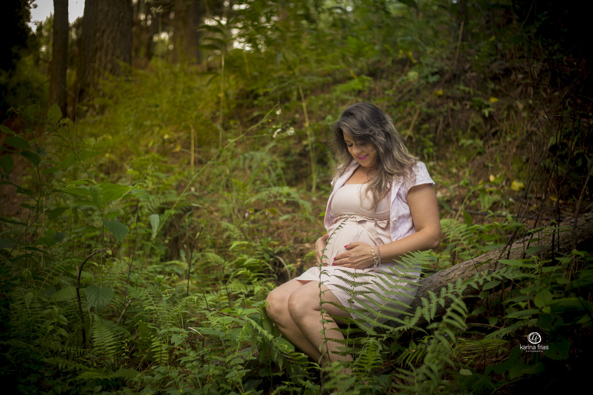 A GESTANTE ESTA SENTADA OLHANDO PARA A BARRIGA NO ENSAIO EXTERNO