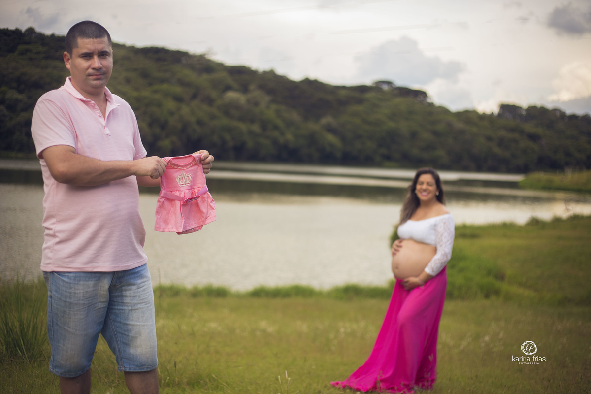 O PAI SEGURA A ROUPA DA CRIANÇA ENQUANTO A MAE ESTA AO FUNDO