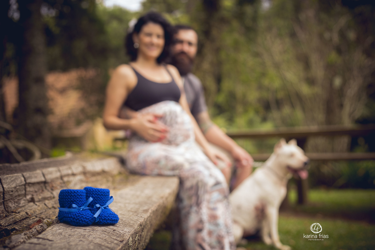os pais ficam ao fundo enquanto a fotografa de gestante fotografa o sapatinho do bebe