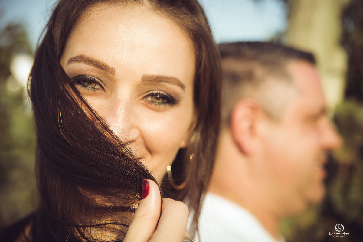 a modelo olha para a camera enquanto o marido fica de lado ao fundo