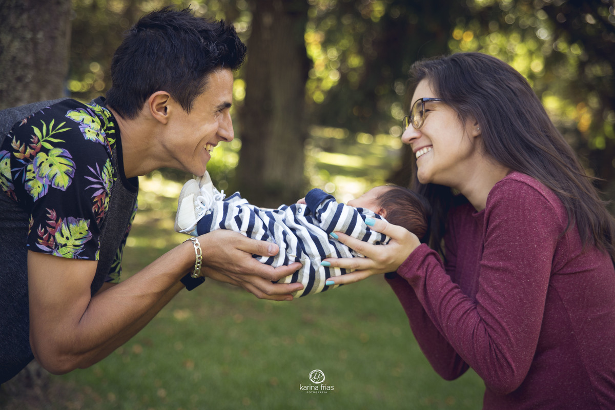 os pais se olham enquanto seguram o bebe no book infantil externo