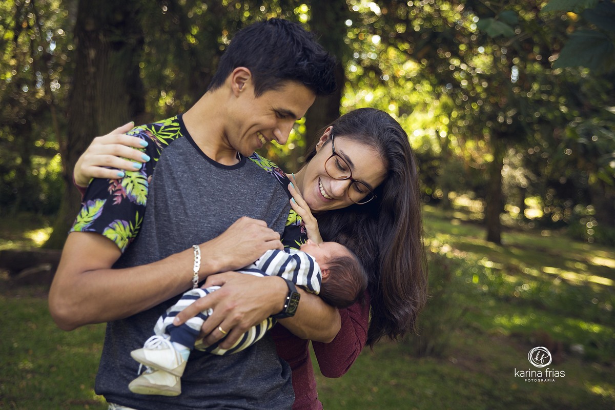 os pais olham o bebe enquanto a fotografa de familia, karina frias de caxias do sul, registra o momento