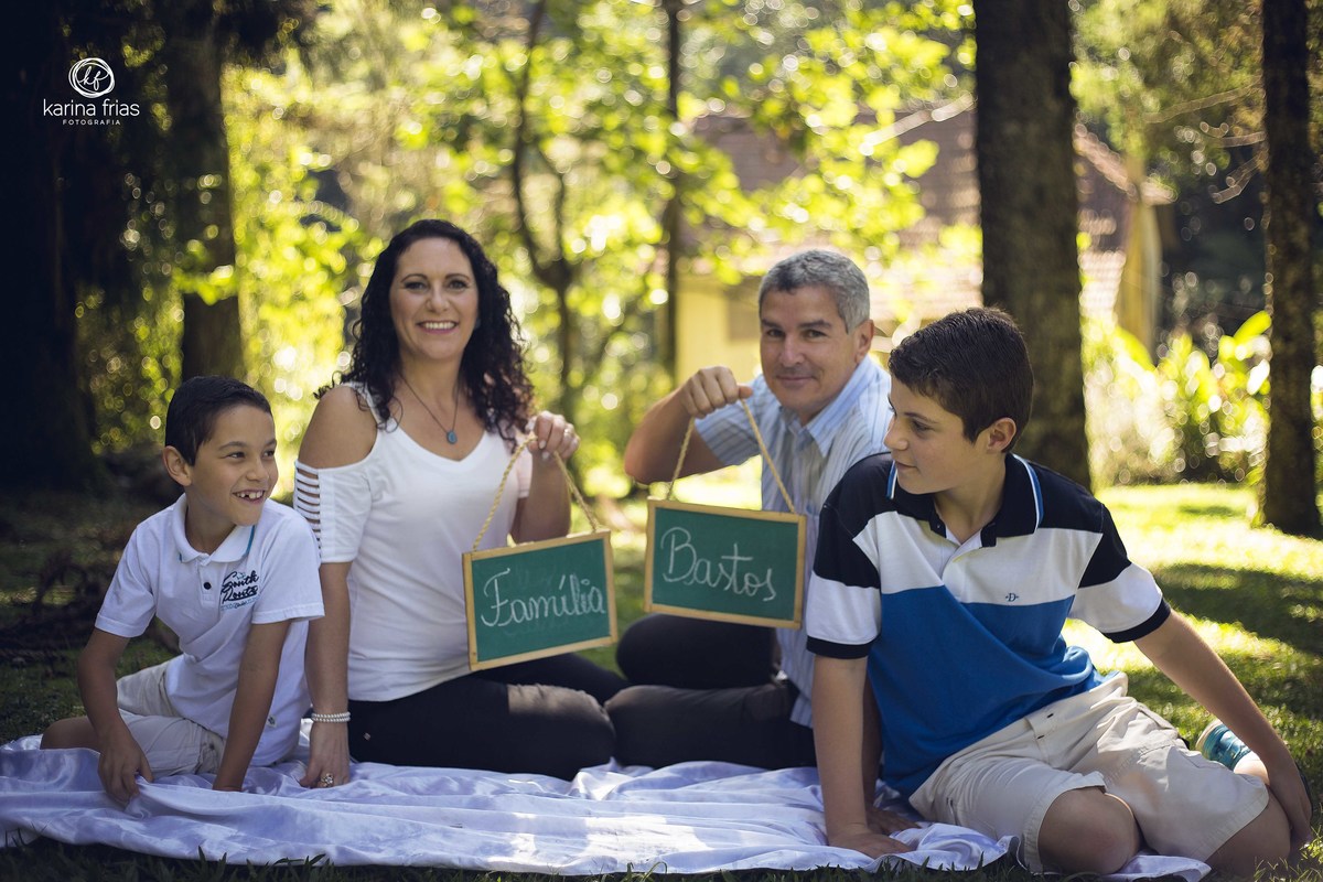 A FAMILIA SEGURA A PLAQUINHA COM SEU SOBRENOME NO ENSAIO DE FAMILIA