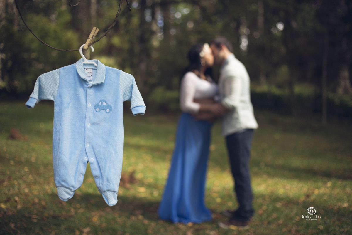 os pais se beijam ao fundo durante sessão de fotos de gestante