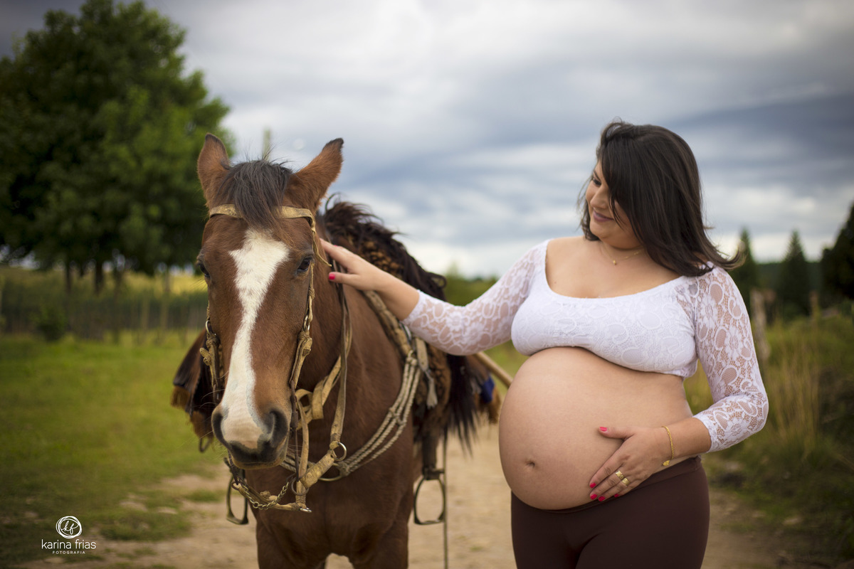a gestante acaricia o cavalo em seu ensaio externo