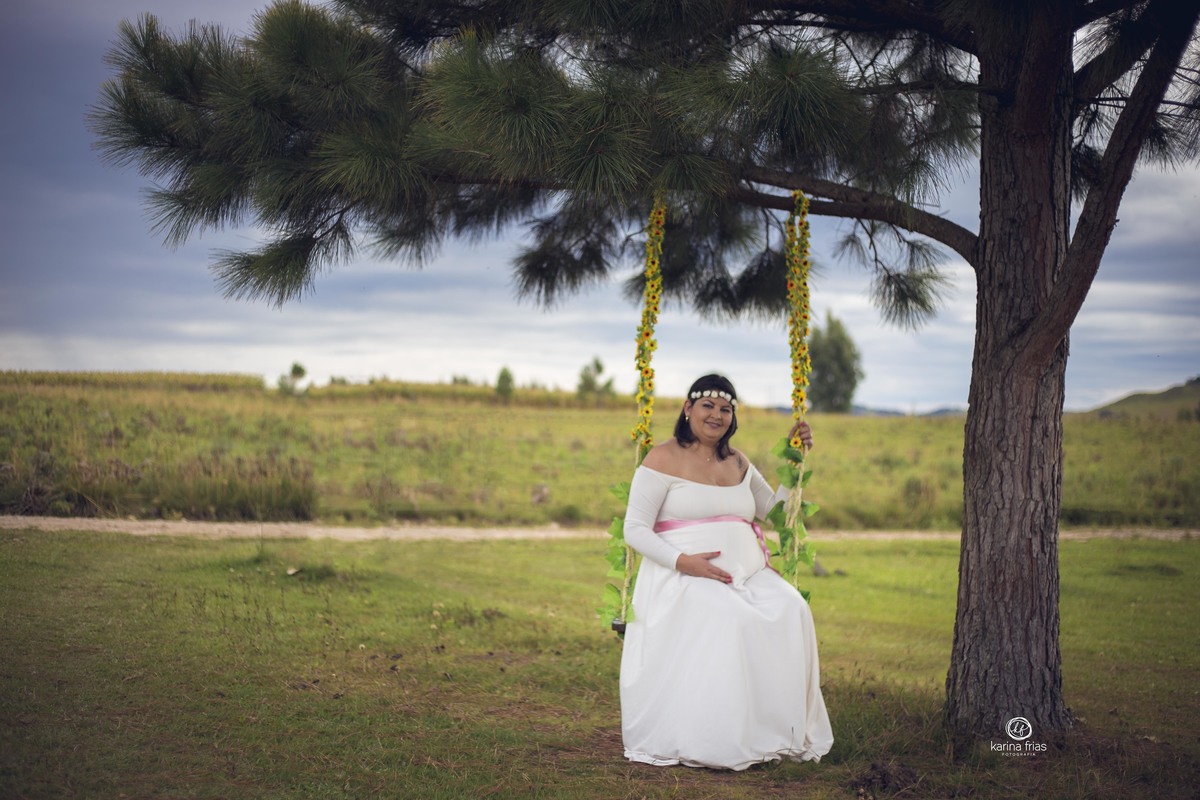 a gestante esta sentada no balanço no seu ensaio
