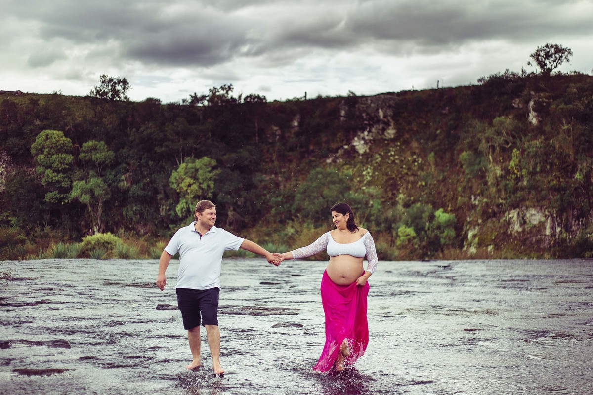 os pais brincam na chuva durante a sessão de fotos de gestante
