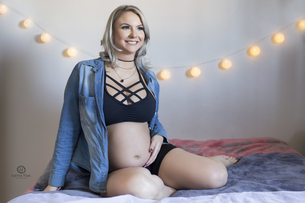 a gestante esta sentada na cama para seu book de gestante