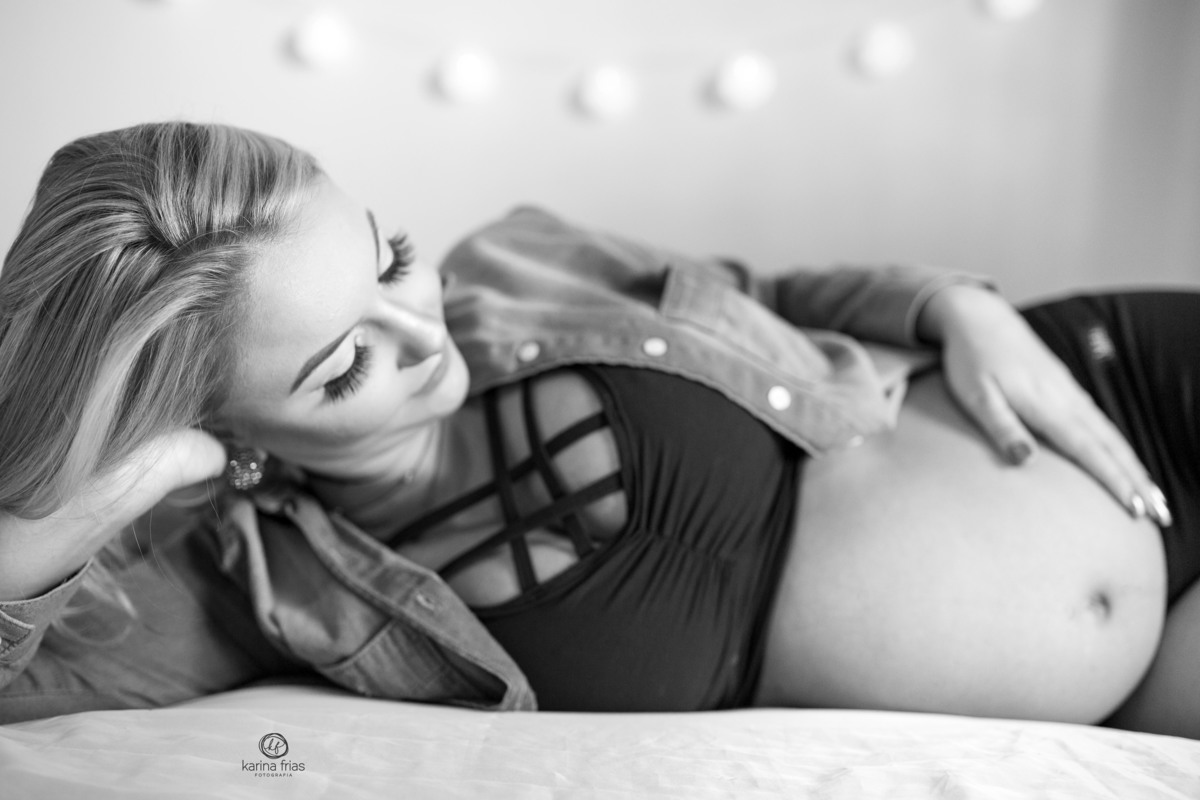 a modelo deita na cama para seu ensaio de gestante