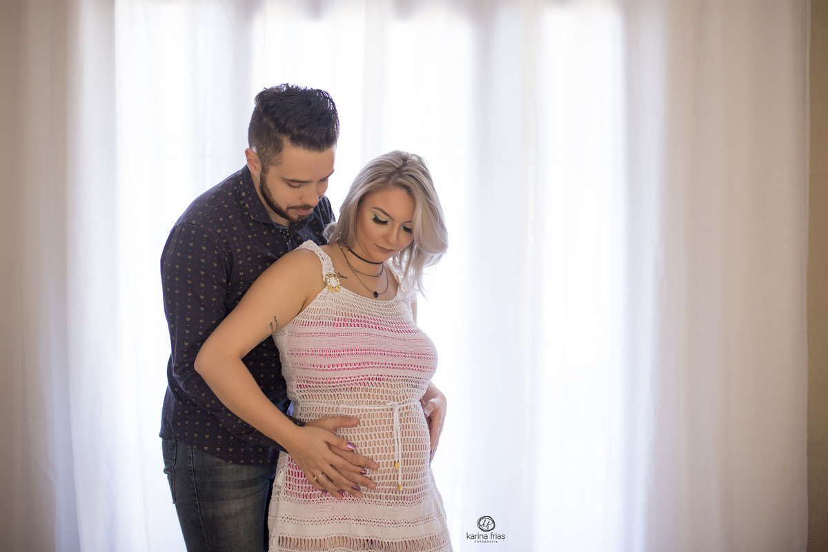 os pais posam frente a janela da casa da gestante