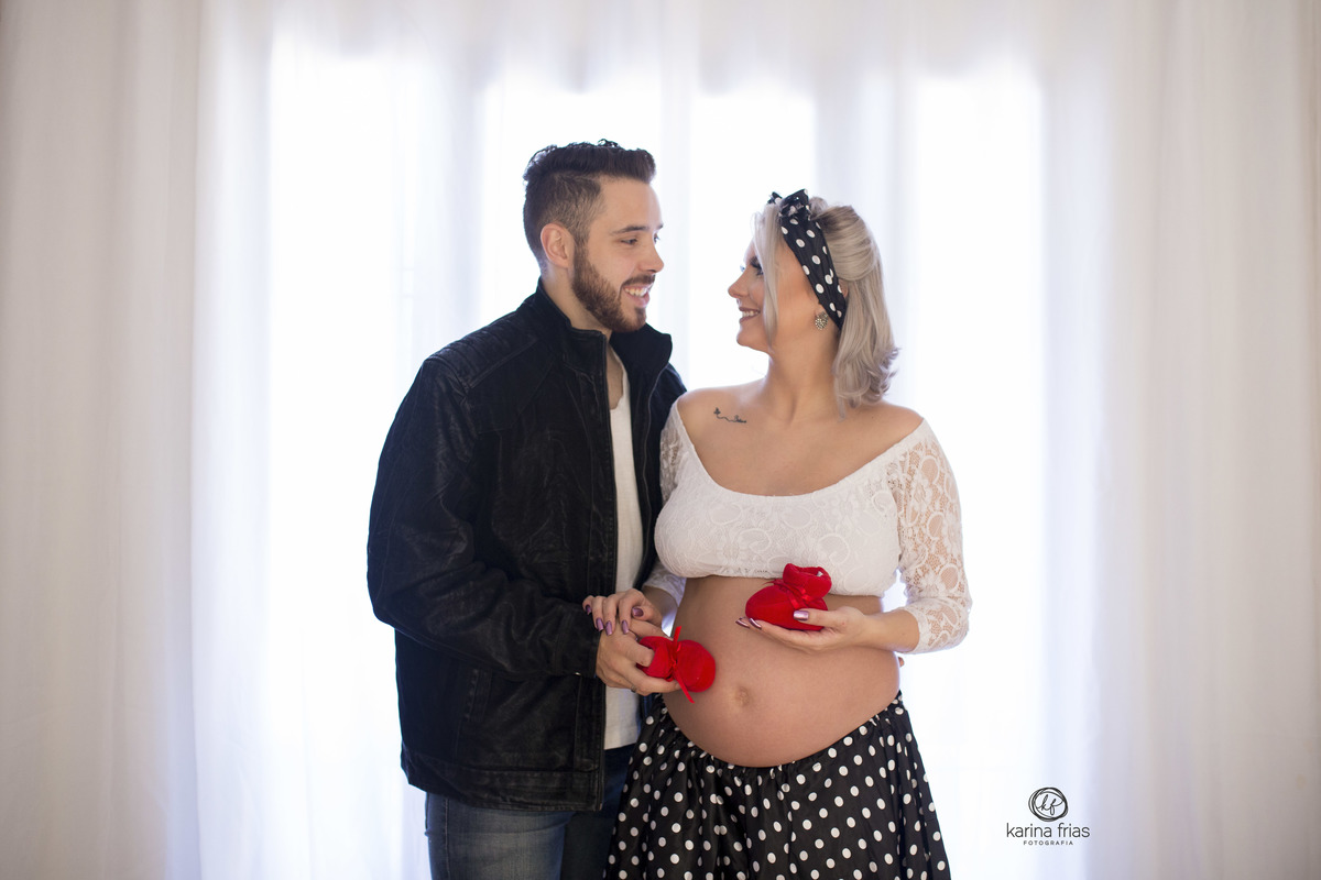 no ensaio externo de gestante pinup os pais seguram os sapatinhos