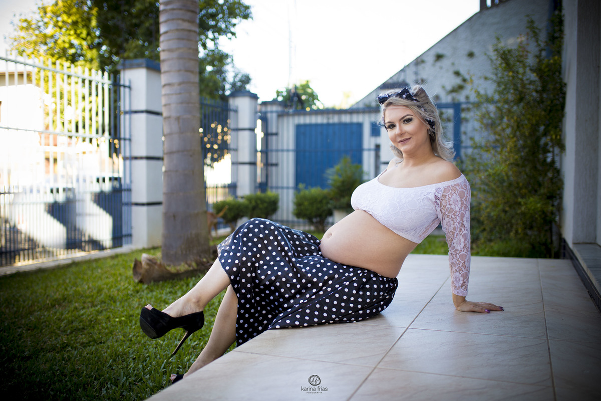 a modelo esta sentada frente sua casa nas fotos externas