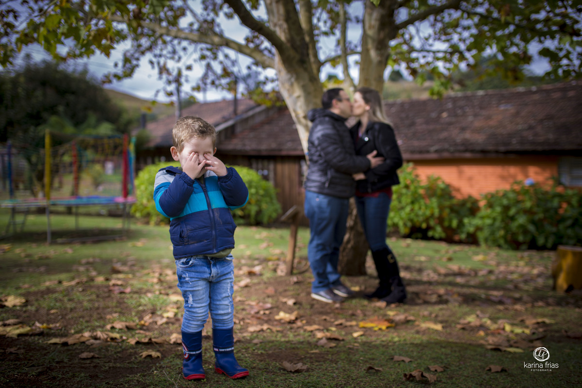 a criança se esconde enquanto os pais se beijam no ensaio de familia