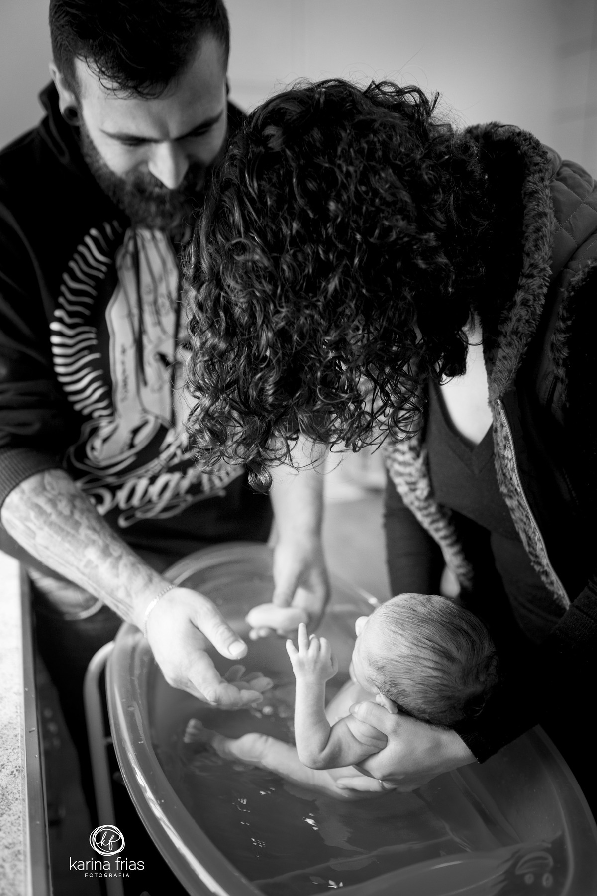 os pais dao banho no bebe e a fotografa de familia registra o momento