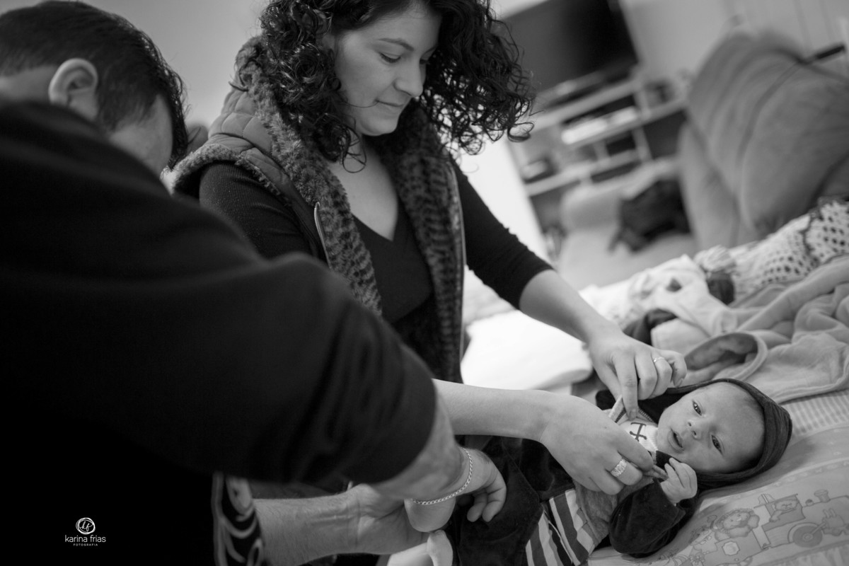 os pais trocam o bebe na sessão de fotos em casa