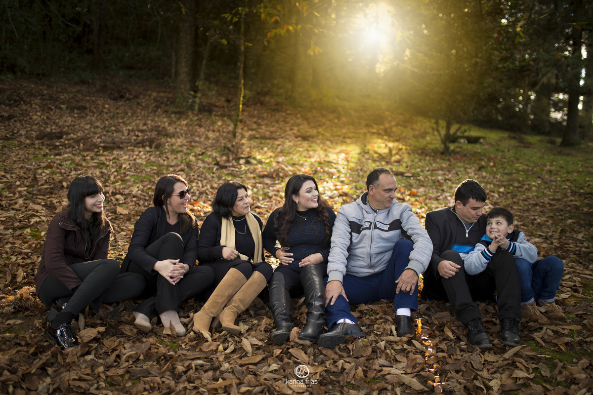 a familia esta sentada, sorrindo enquanto a fotografa registra o momento