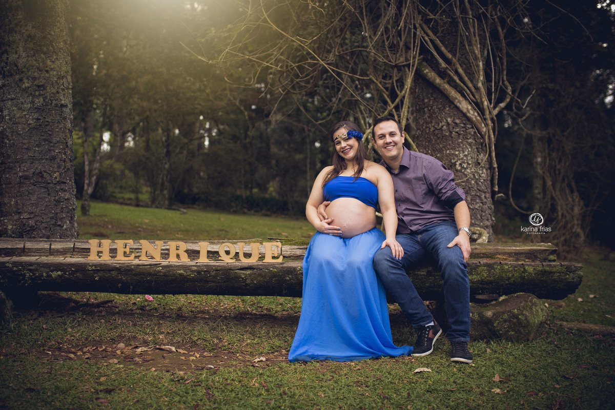 os pais estao sentados ao lado do letreiro no ensaio de gestante externo