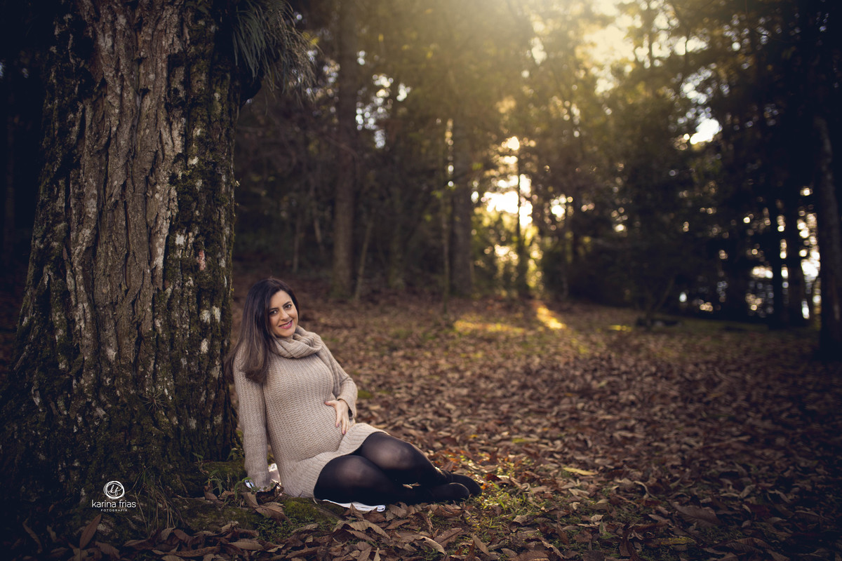 A GESTANTE ESTA SENTADA ENQUANTO A FOTOGRAFA DE FAMILIA DE CAXIAS DO SUL-RS CAPTURA O MOMENTO