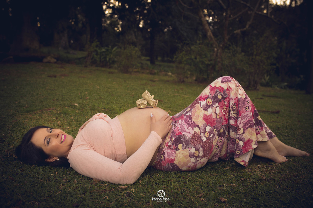 os sapatinhos da bebe estao em cima da barriga para sessão de fotos de gestante