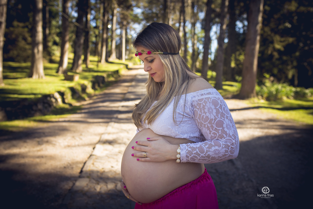 a gestante olha para a barriguinha durante ensaio externo