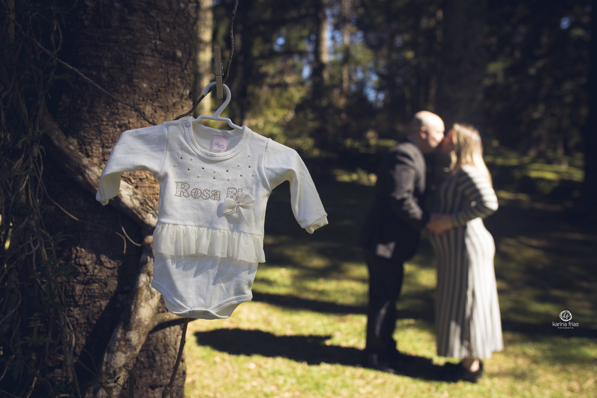 a roupa da bebe esta focada e os pais se beijam ao fundo