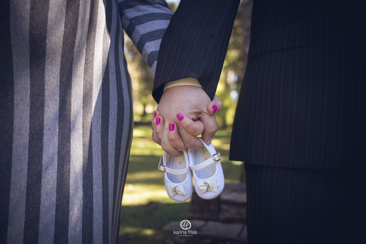 os pais seguram os sapatinhos da bebe no ensaio externo