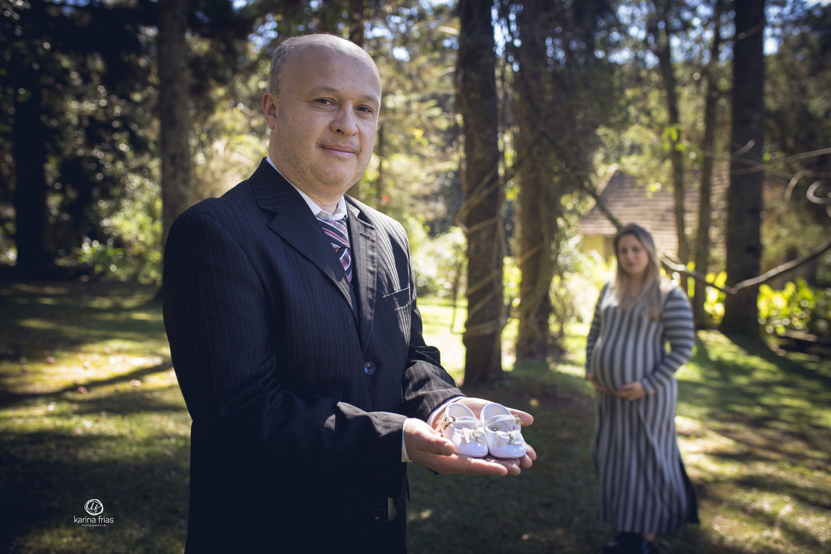 o pai mostra o sapatinho e a gestante olha ao fundo no seu book externo