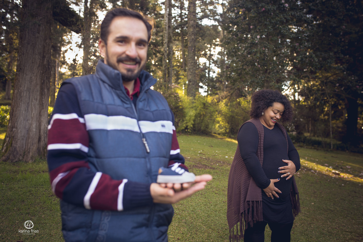 o pai segura o sapatinho do bebe no ensaio de gestante