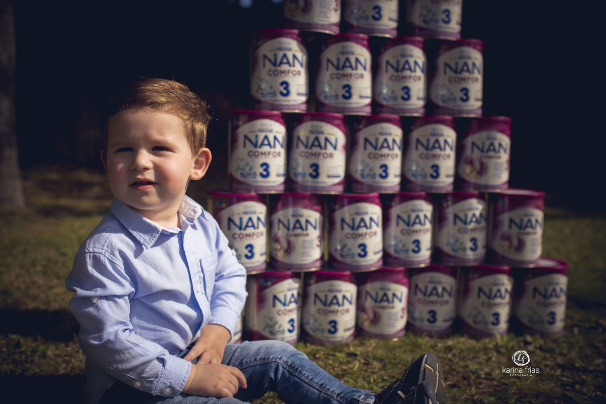 A CRIANÇA ESTA SENTADA PERTO DAS LATAS DE LEITE PARA O ENSAIO INFANTIL