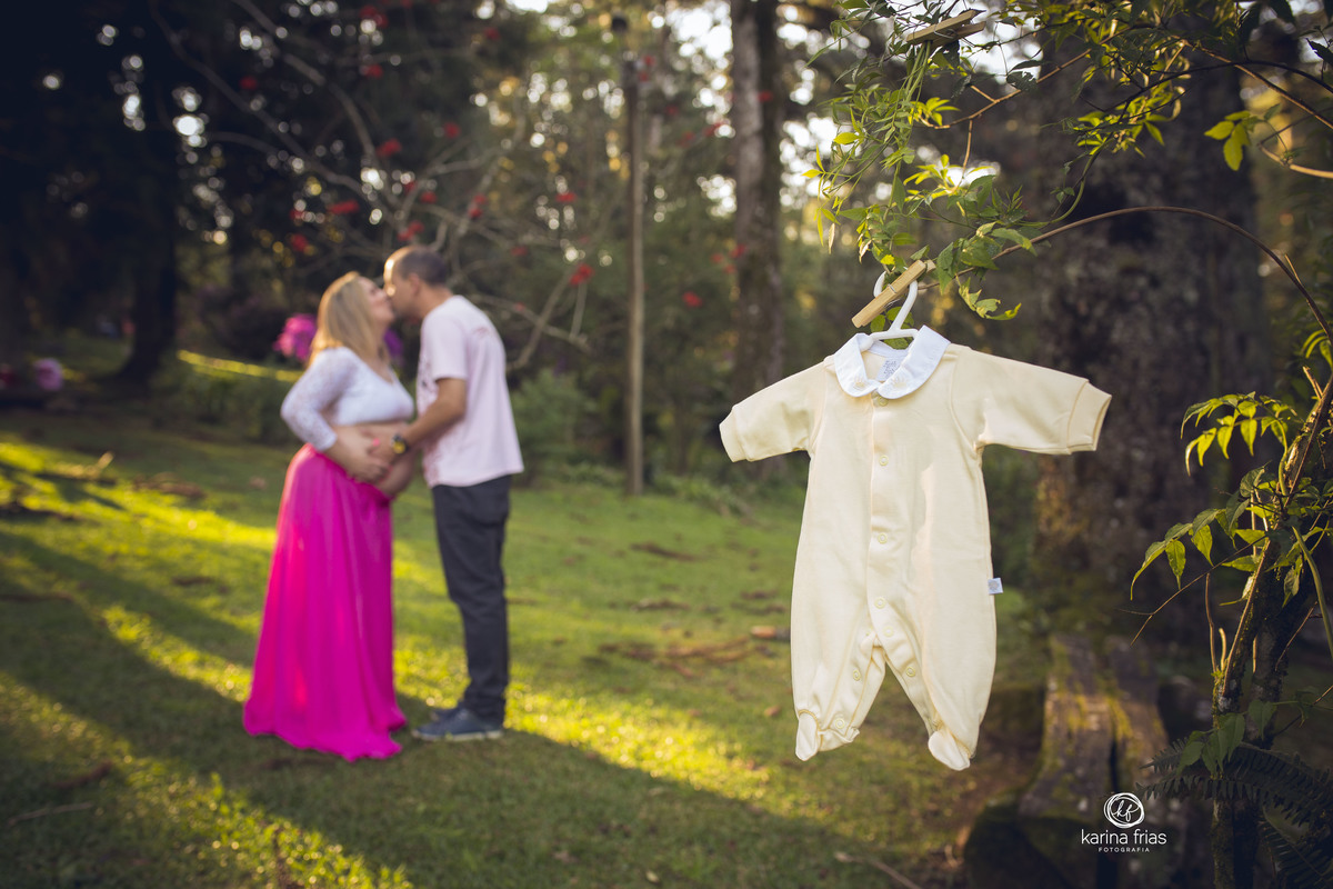 AO FUNDO FICAM OS PAIS E NA FRENTE A ROUPA DO BEBE