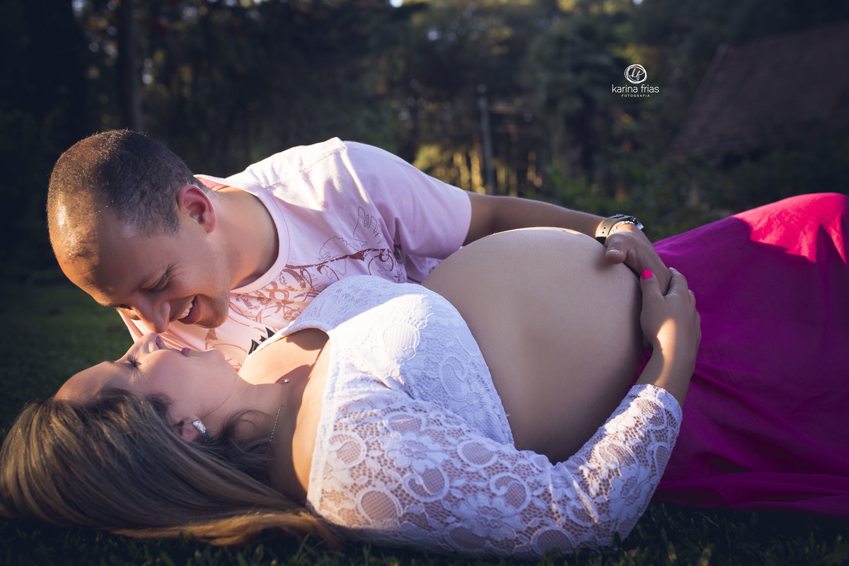 OS PAIS ESTAO DEITADOS ENQUANTO A FOTOGRAFA DE FAMILIA DE CAXIAS DO SUL, KARINA FRIAS REGISTRA O MOMENTO NO ENSAIO DE GESTANTE