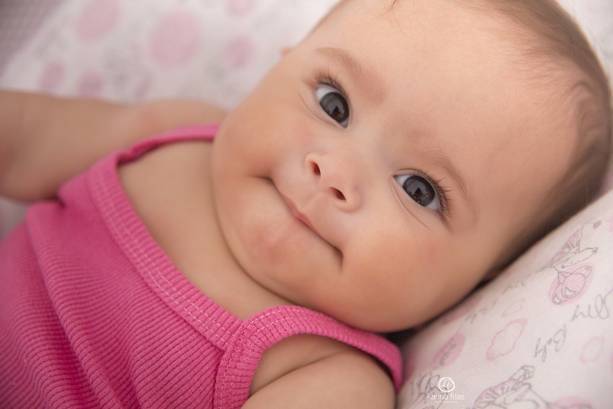 NO ACOMPANHAMENTO MENSAL A MENINA OLHA PARA A FOTOGRAFA DE FAMILIA, KARINA FRIAS