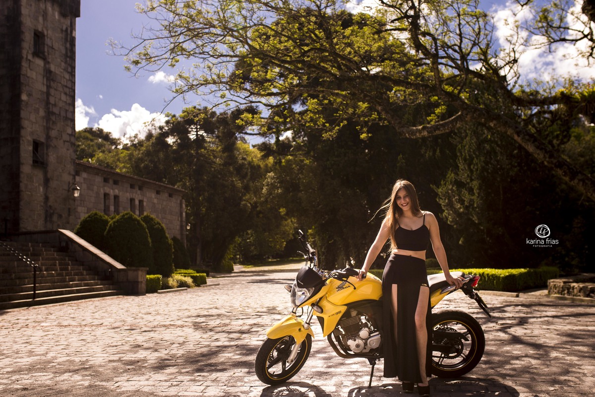 a modelo esta apoiada na moto no seu ensaio externo de 15