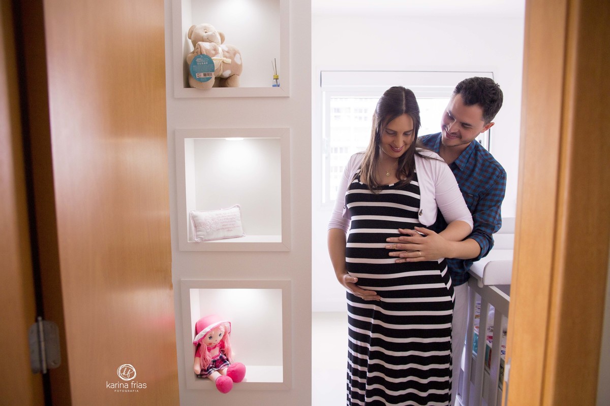 os pais estao no quarto da bebe para sessão de fotos