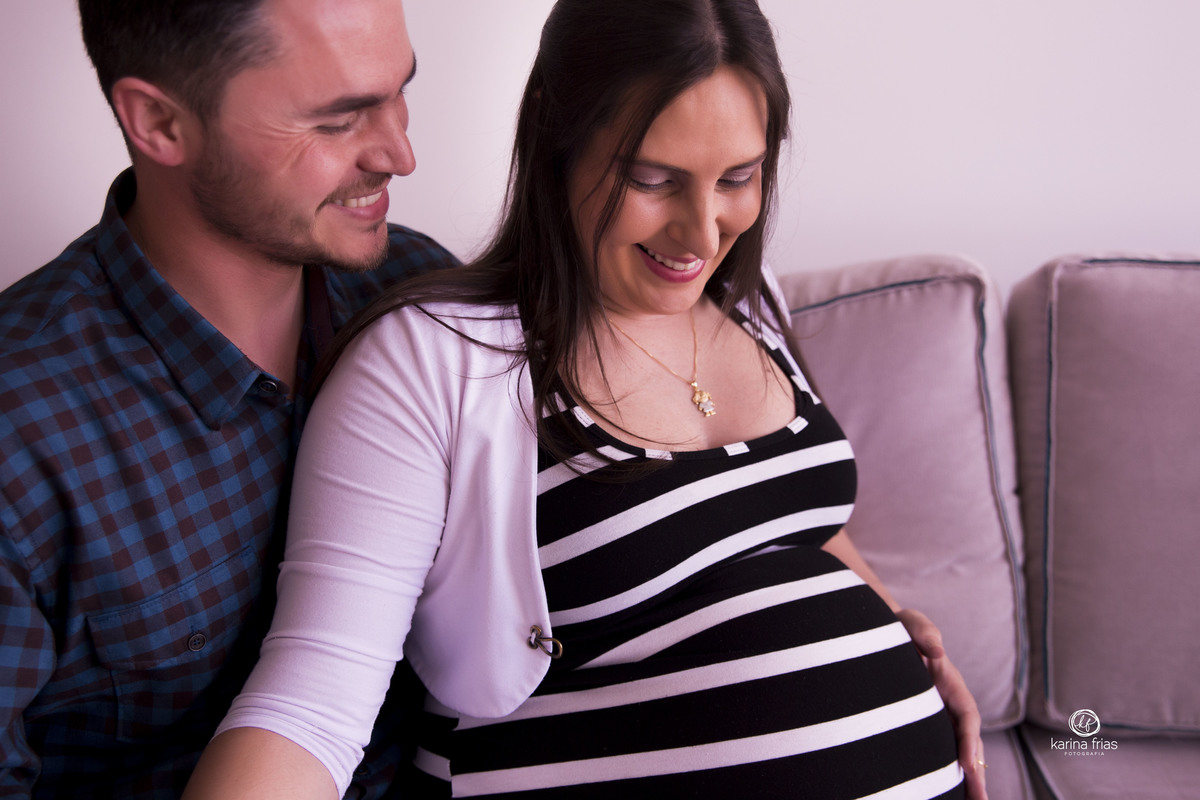 o casal sorri para as fotos de gestante