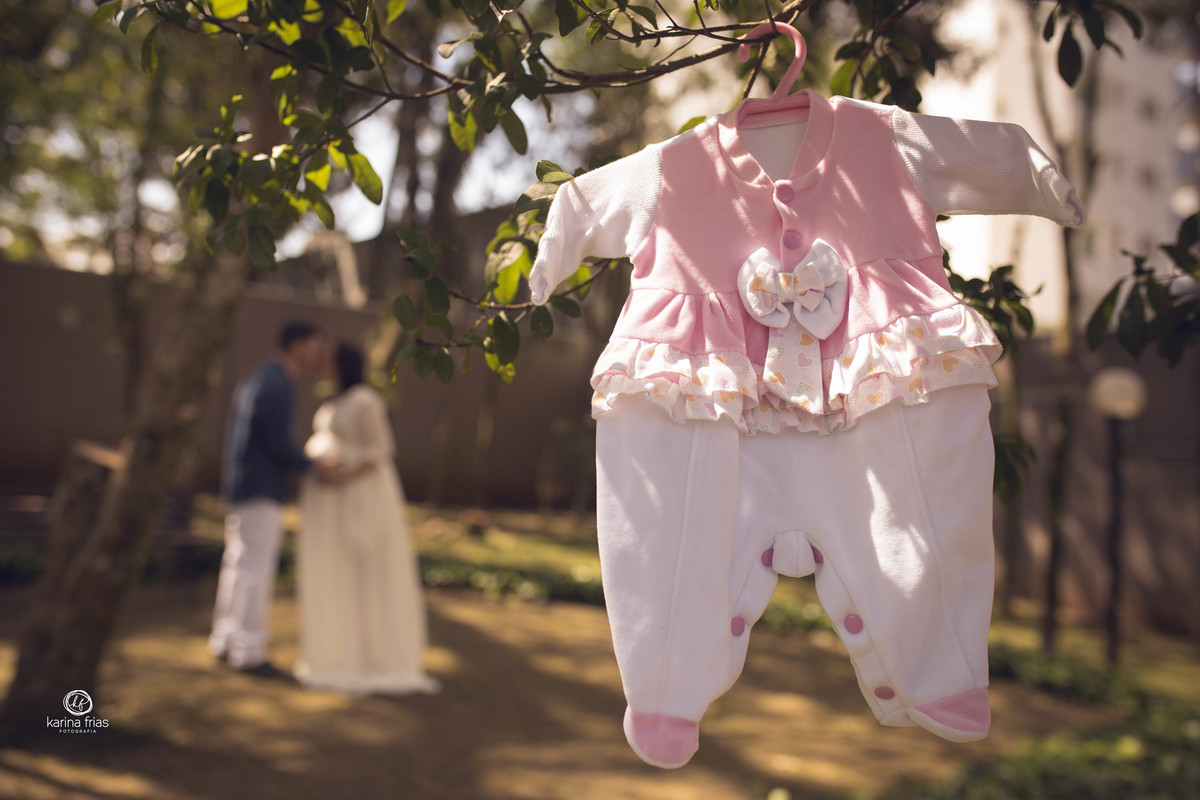 os pais estao ao fundo e na frente a roupinha da bebe