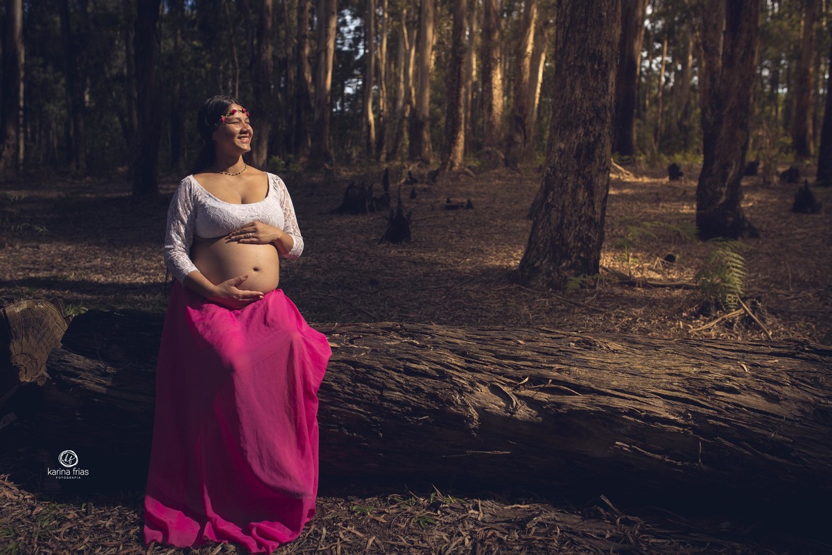 A GESTANTE ESTA SENTADA SENTINDO  O SOL DURANTE A SESSÃO DE FOTOS