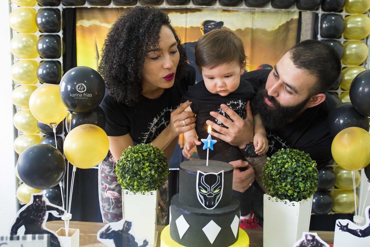 os pais e a criança assopram as velinhas do aniversario